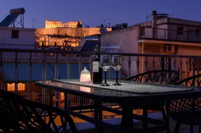 a table with a bottle of wine and two glasses at Acropolis View Penthouse in Athens
