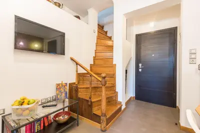 a hallway with a staircase with a television and a door at Amazing Acropolis View from Exarcheia in Athens