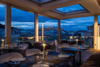 a restaurant with tables and chairs and a view of the city at Heritage Hill Hotel in Athens