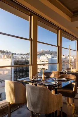 a restaurant with tables and chairs and large windows at Heritage Hill Hotel in Athens