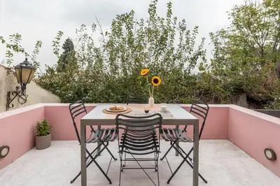a table and chairs on a balcony with pink walls at Anafiotika hideaway acropolis Athens by Cycladica in Athens