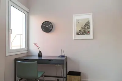 a desk with a chair and a clock on a wall at Gazi District Next To Subway 2 in Athens