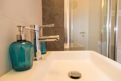 a bathroom sink with a soap bottle and a mirror at Gazi District Next To Subway 2 in Athens