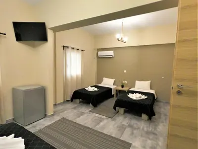 a room with two beds and a flat screen tv at Achillion Hotel Piraeus in Piraeus