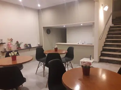 a waiting room with tables and chairs and stairs at Achillion Hotel Piraeus in Piraeus