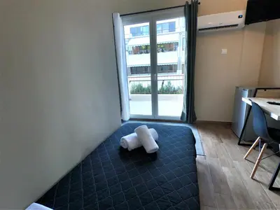 a teddy bear laying on a bed in a room with a window at Achillion Hotel Piraeus in Piraeus