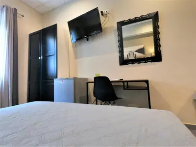 a bedroom with a bed and a desk and a mirror at Achillion Hotel Piraeus in Piraeus