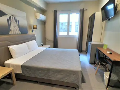 a bedroom with a bed and a desk and a television at Achillion Hotel Piraeus in Piraeus