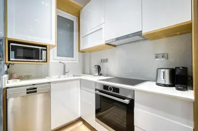 a kitchen with white cabinets and a sink and a stove at Stylish, Sunny New 2 Bedroom, Prime Central Athens in Athens