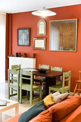 a dining room with orange walls and a table and chairs at Homie Apartment next to Acropolis in Athens