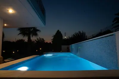a swimming pool lit up at night in a house at Luxury heated pool Villa in Lagonissi