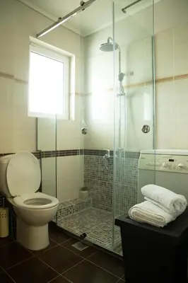 a bathroom with a toilet and a glass shower at Luxury heated pool Villa in Lagonissi