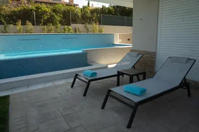 two chairs and a table next to a swimming pool at Luxury heated pool Villa in Lagonissi