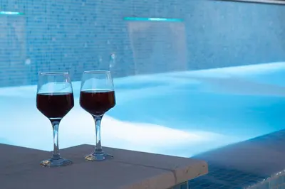 two glasses of wine sitting on a table next to a pool at Luxury heated pool Villa in Lagonissi