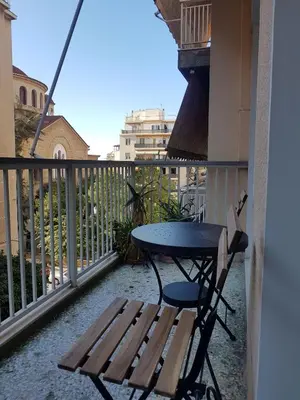 a table and a chair on a balcony with a table and bench at Colourful Apartment in the heart of Athens in Athens