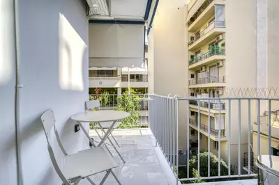 a balcony with a table and chairs and a building at Bright Spacious Luxury Apartment in Prime Central Athens in Athens