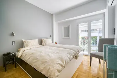 a white bedroom with a large bed and a chair at Bright Spacious Luxury Apartment in Prime Central Athens in Athens