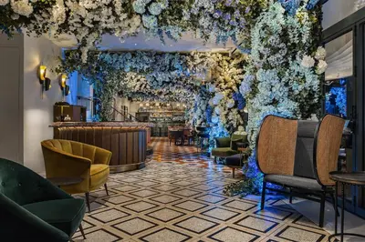 a lobby with a bar with flowers on the wall at Gatsby Athens in Athens