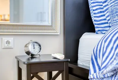 a alarm clock on a table next to a bed at Lovely Sunlit Central Athens 2 Bedroom 2 Bathroom Condo in Athens