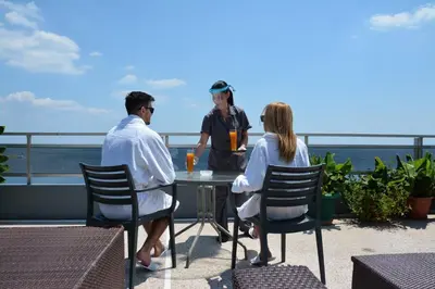 a couple of people sitting at a table on a roof at Scorpios Sea Side Hotel in Piraeus