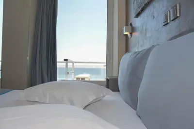 two beds in a hotel room with a large window at Scorpios Sea Side Hotel in Piraeus