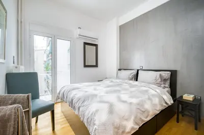 a bedroom with a bed and a chair and a window at Delightful Stylish Two Bedroom Condo in Hip Area of Central Athens in Athens
