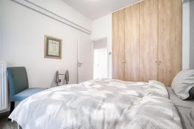 a bedroom with a white bed and a blue chair at Delightful Stylish Two Bedroom Condo in Hip Area of Central Athens in Athens