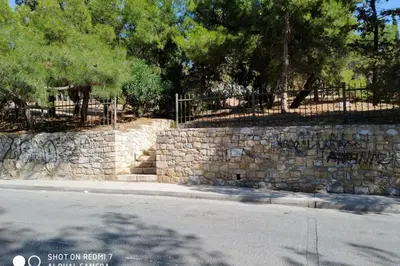 a stone retaining wall with trees and a fence at Vasilis Thissio Petralona 3d floor 55sqm in Athens