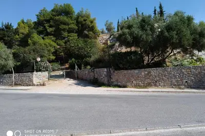 a stone wall next to a street with trees at Vasilis Thissio Petralona 3d floor 55sqm in Athens