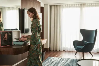 a woman in a green dress standing in front of a machine at Athens Capital Center Hotel - MGallery Collection in Athens