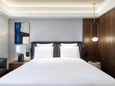 a bedroom with a large bed with white sheets at Athens Capital Center Hotel - MGallery Collection in Athens