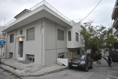 a white house with a car parked in front of it at Rock, few steps from Acropolis rocks! in Athens
