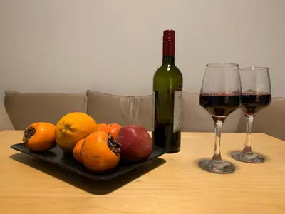 a table with a plate of fruit and a bottle of wine at Treasure cosy flat in Athens