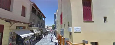 a group of people walking down a street between buildings at Check Point - Plaka in Athens