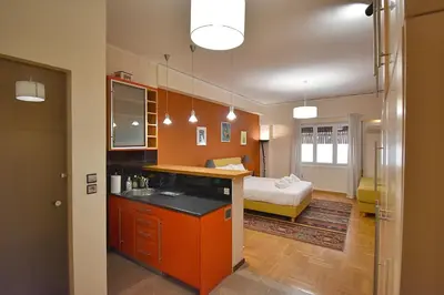 a kitchen with orange cabinets and a bed in a room at Check Point - Down Town in Athens