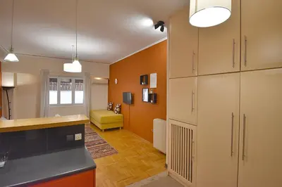 a kitchen with orange walls and white cabinets at Check Point - Down Town in Athens