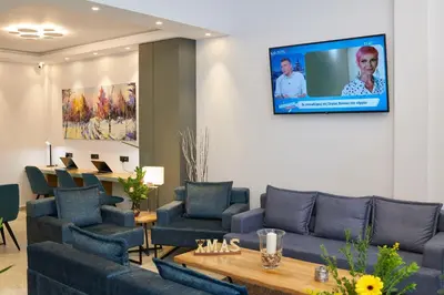 a waiting room with blue couches and a tv on the wall at Meni Hotel & Apartments UNDER NEW MANAGEMENT in Athens