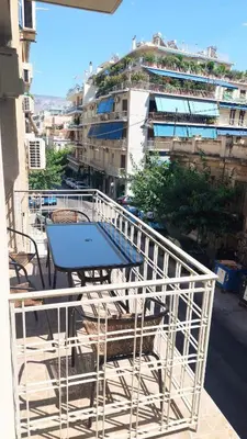 a table and chairs on a balcony with a building at Comfortable apartment in Acropolis in Athens