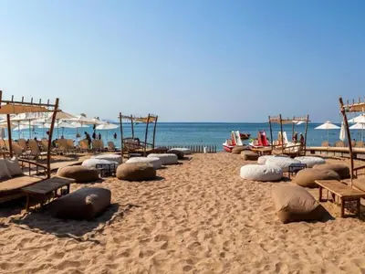 a sandy beach with benches and umbrellas and the ocean at Thelfi Luxury studio in Attica - close to varkiza beach - Sea view in Vari