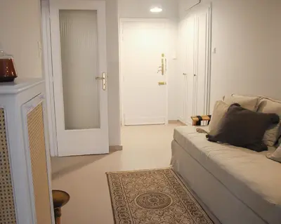 a white living room with a couch and a mirror at API Projects Athens - Parliament Apartment in Athens
