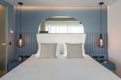 a bedroom with a white bed with a blue wall at Urban Suites in Athens