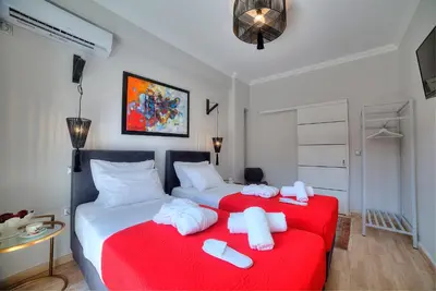 a bedroom with two beds with red sheets and white towels at Amazing apartment in Glyfada center in Athens