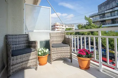 a balcony with two wicker chairs and flowers on it at Amazing apartment in Glyfada center in Athens