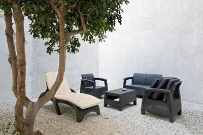 a group of chairs and a tree next to a wall at Poseidon Residence in Athens