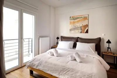 a white bedroom with a large bed with white pillows at Poseidon Residence in Athens