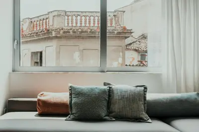 a couch in front of a window with a view of a building at Stylish Suite, by MGM Residencies in Athens