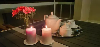 a table with three candles and a vase with flowers at The Six Museums central Athens Stadium 4pers apart in Athens