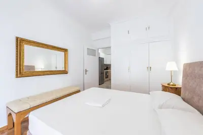 a white bedroom with a bed and a mirror at Victoria Supreme Suite in Athens