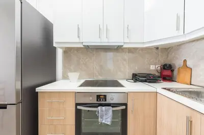 a kitchen with a stove and a sink and white cabinets at Victoria Supreme Suite in Athens