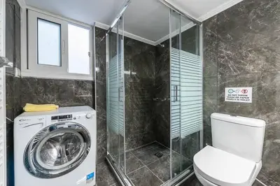 a bathroom with a washing machine and a shower at Victoria Supreme Suite in Athens